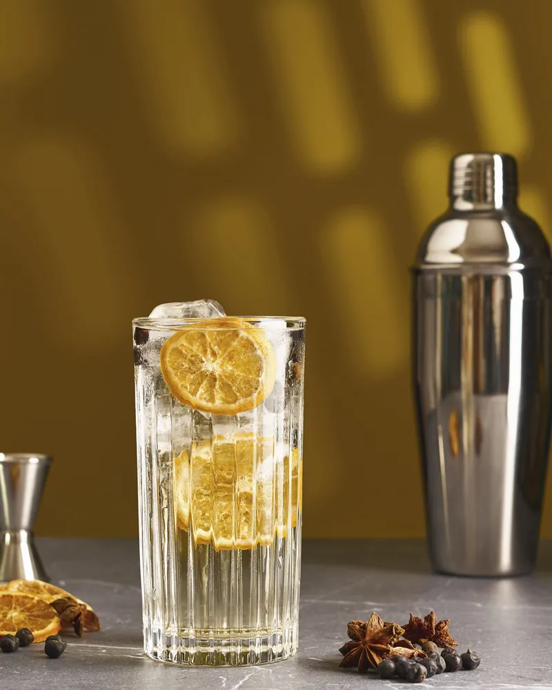Cocktail agli agrumi con shaker su fondo ocra