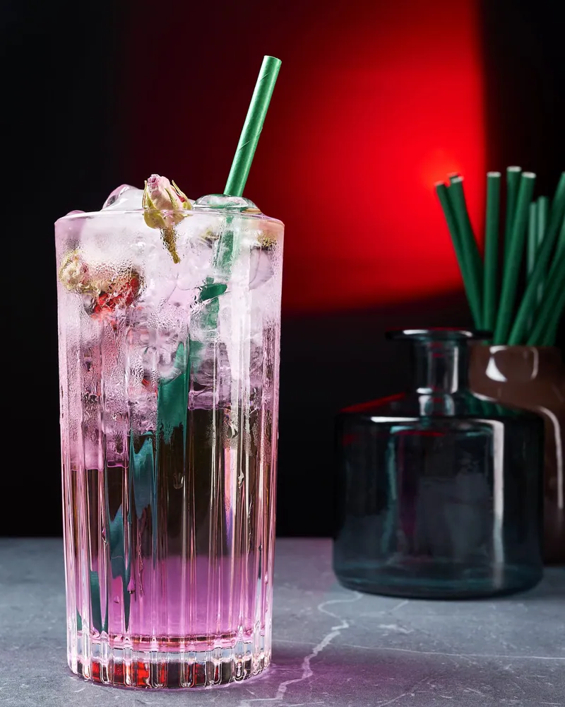 Long drink rosa con cannuccia verde su fondo rosso