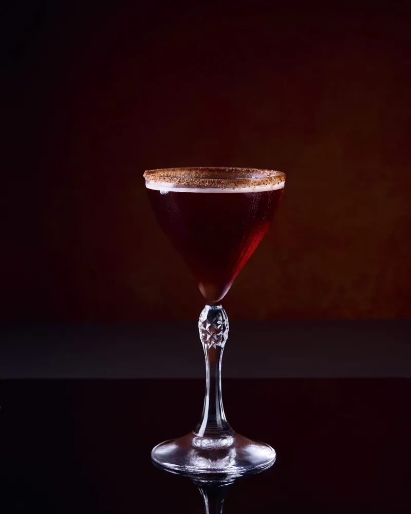 Cocktail rosso in coppa su fondo scuro