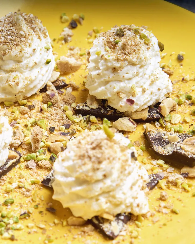 Dolci con meringa e granella di pistacchio su fondo giallo