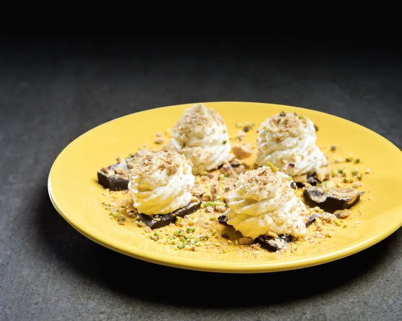 Dessert con meringhe su piatto giallo e fondo scuro