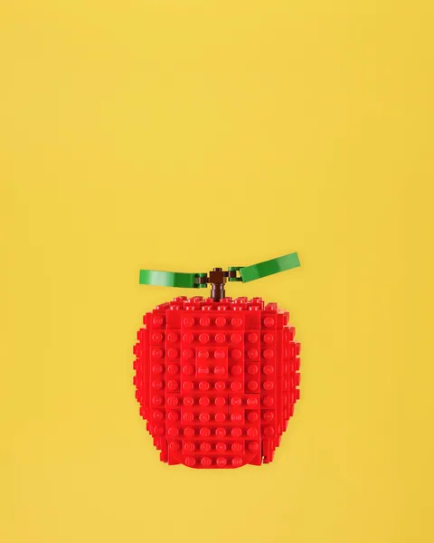 Mela rossa costruita con mattoncini LEGO su fondale giallo