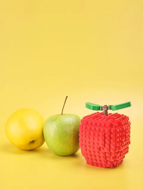 Mela gialla, mela verde e mela LEGO su fondale giallo
