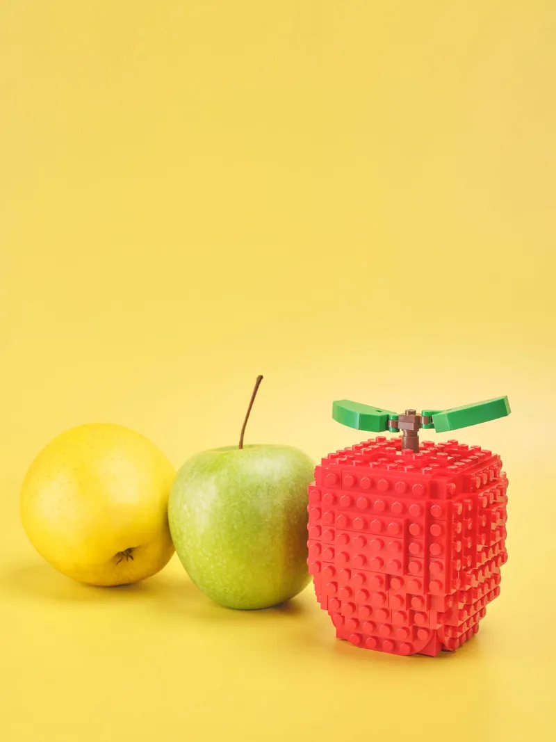 Mela gialla, mela verde e mela LEGO su fondale giallo