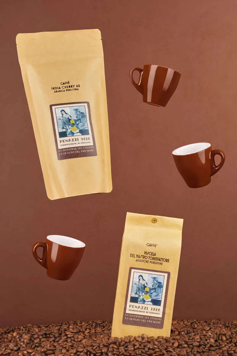 Sacchetti di caffè Penazzi e tazzine sospesi su fondale marrone