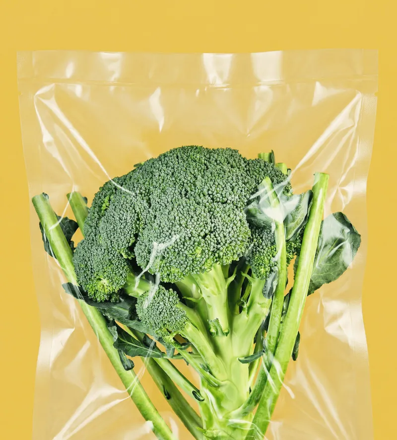 Broccolo in busta trasparente sottovuoto su sfondo giallo.
