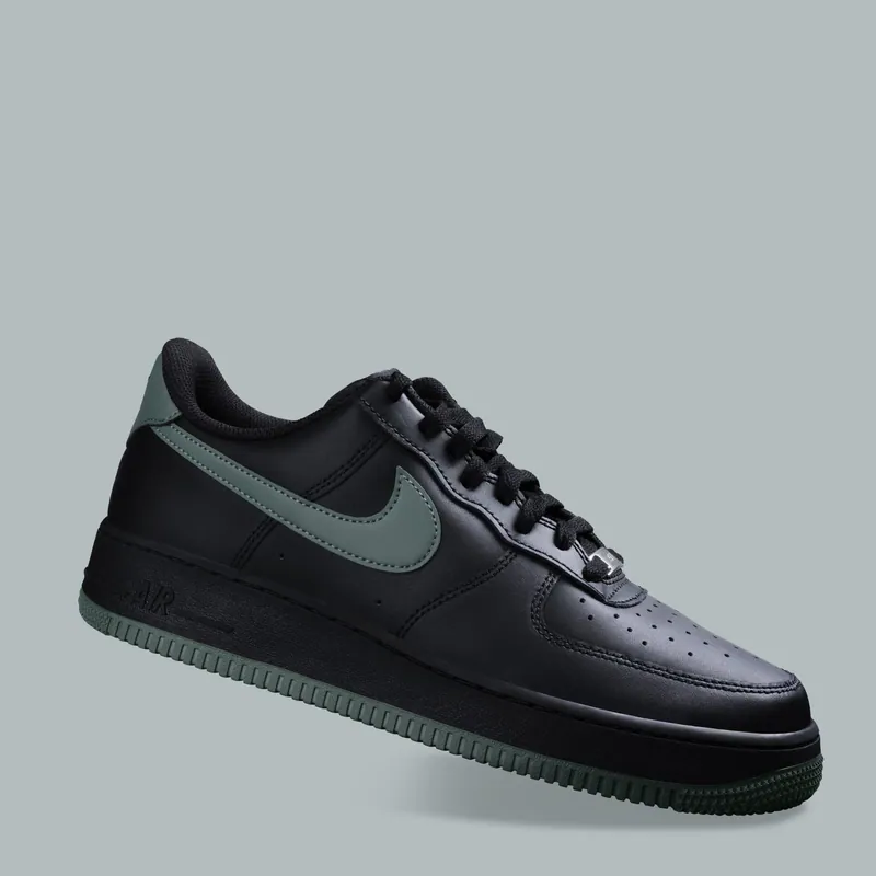 Sneaker nera sospesa su fondale grigio azzurro