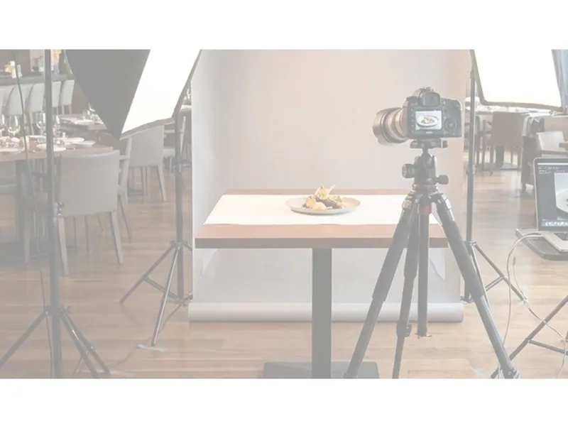 Studio mobile montato in una sala: fotocamera su treppiede davanti al tavolo di scatto