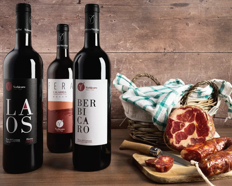 Bottiglie di vino Verbicaro ambientate con salumi su tavolo di legno