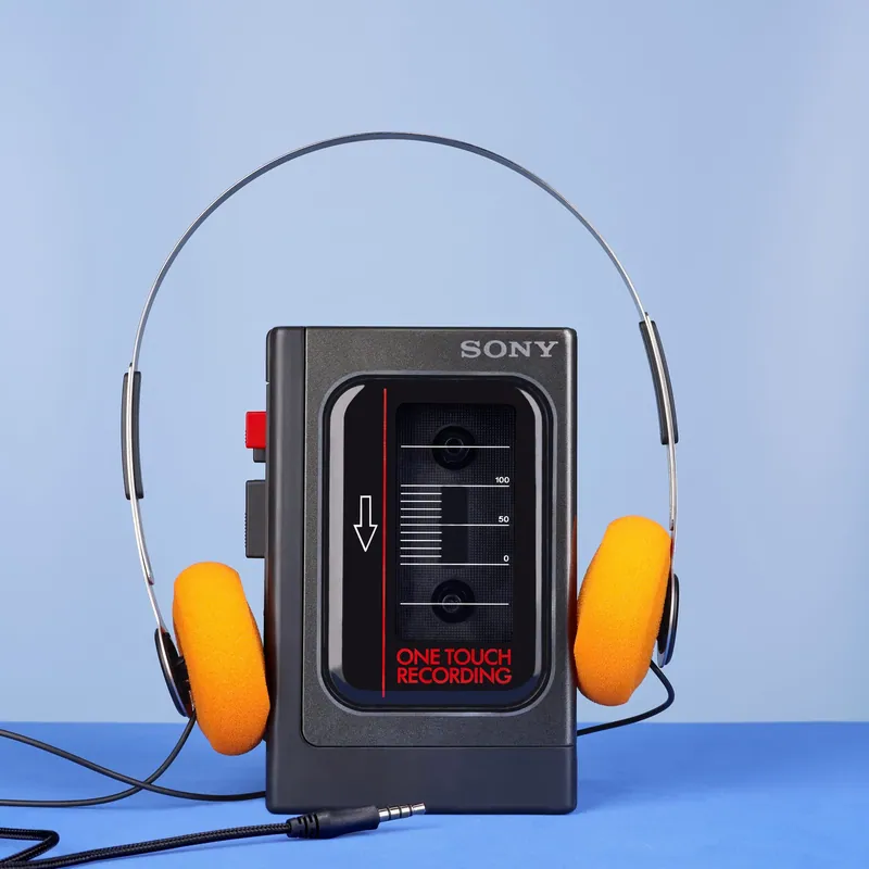 Walkman Sony con cuffie arancioni su fondale azzurro